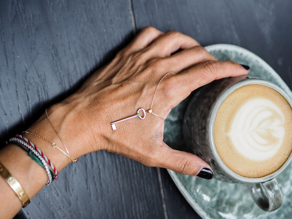 Tiba Jewelry key necklace beside a cup of coffee